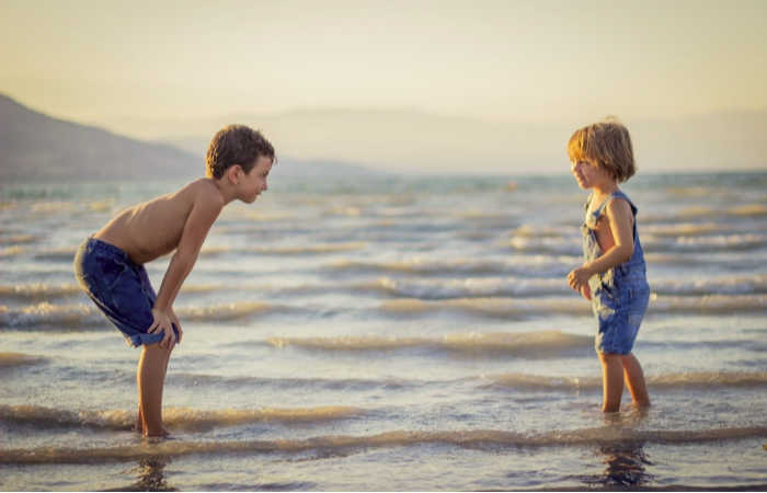 Two boys playing together at the beach. Photo by Limor Zellermayer on Unsplash