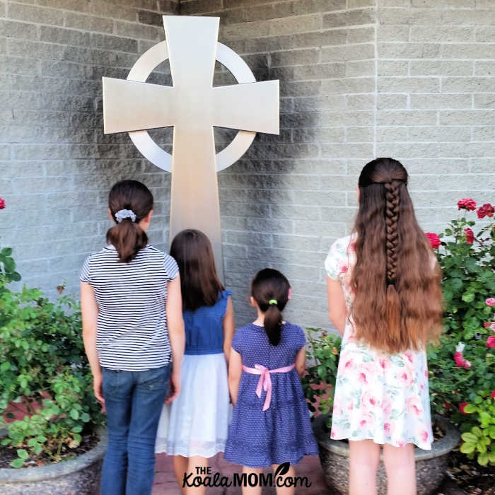 Girls looking at a cross in their Sunday best.