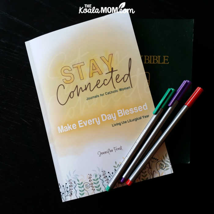 Stay Connected Journals for Catholic Women: Make Every Day Blessed - Living the Liturgical Year by Jennifer Frost with a Bible and three colourful pens.