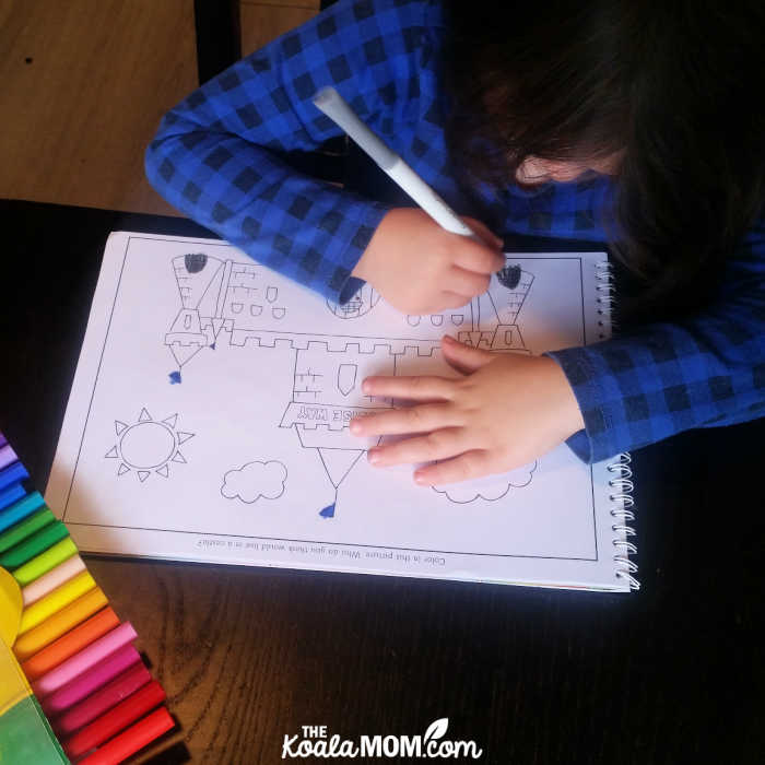 Kindergartener colours a castle in her personalized coloring book.