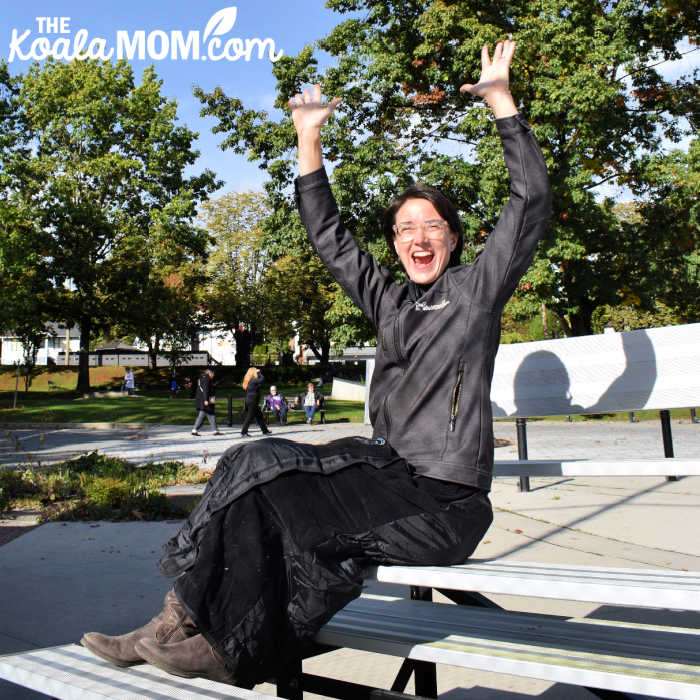 Mom cheering for her child at a sports game while wearing a Mozy blanket around her waist.