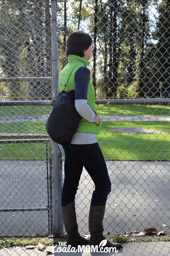 Mom watching her child's game with the Mozy in its pocket over her shoulder.