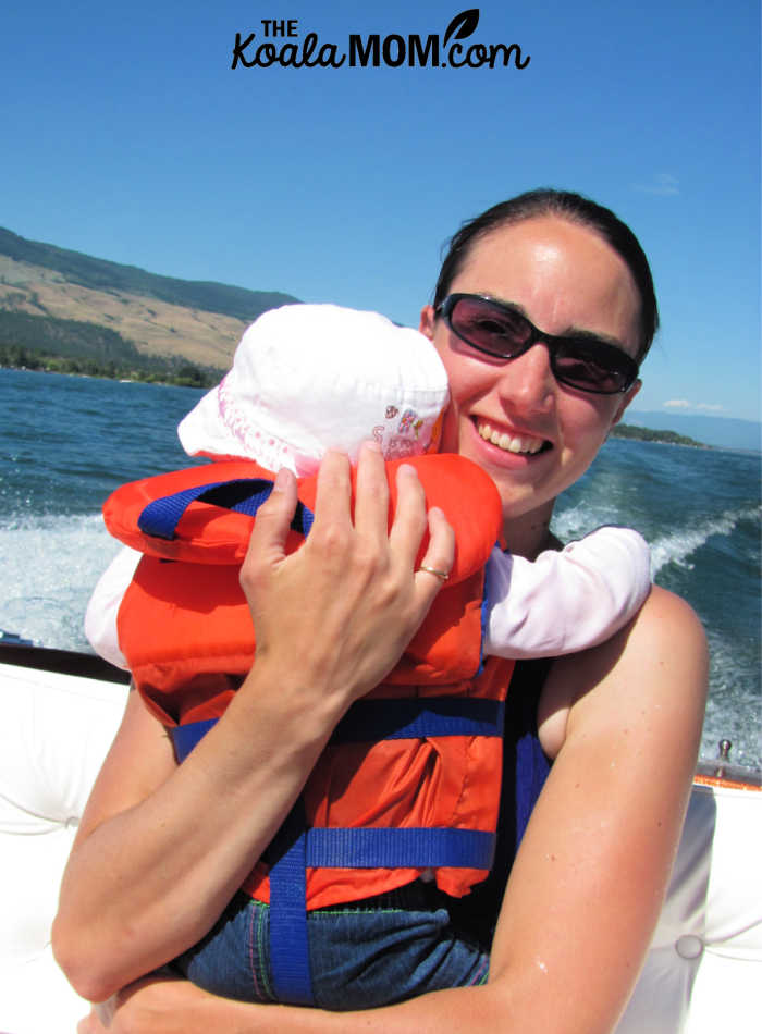 Mom holding her toddler in a PFD while riding in a motor boat.