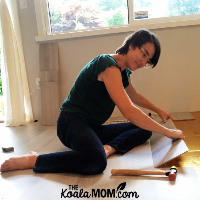 Woman installing laminate flooring in her condo.