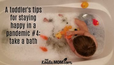 A toddler's tips for staying happy in a pandemic #4: take a bath (like this toddler playing with his goldfish and rubber duckies in a buble bath).