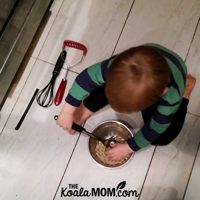 Toddler whipping up a batch of cheerios and rice krispies in the kitchen.