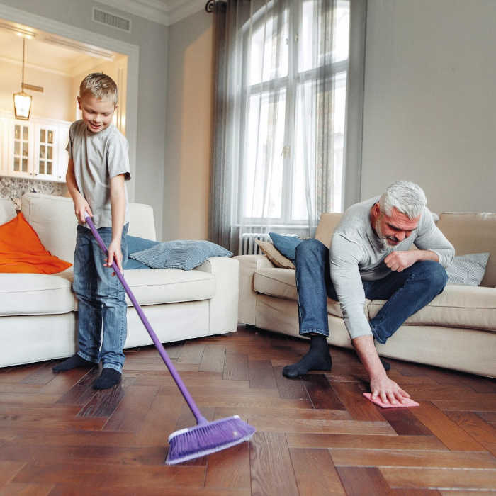 Father and son cleaning a clutter-free living room together.