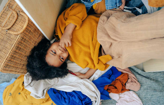 9 Signs That You're Living in a Cluttered Home - your kids are playing in mountains of laundry, like this child.