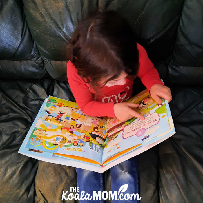 5-year-old looks at a seek and find counting book.