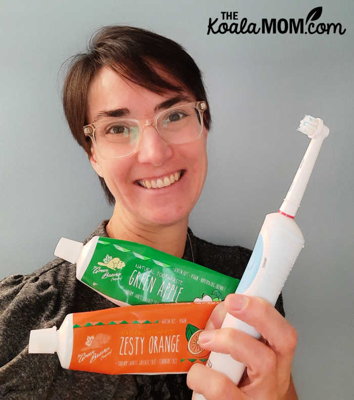 Bonnie holds her electric toothpaste and her favourite Green Beaver toothpaste flavours: Zesty Orange and Green Apple