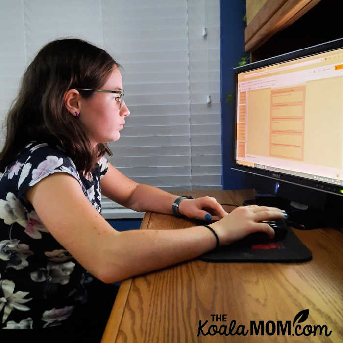 Teen wearing blue light glasses while doing her homework online.