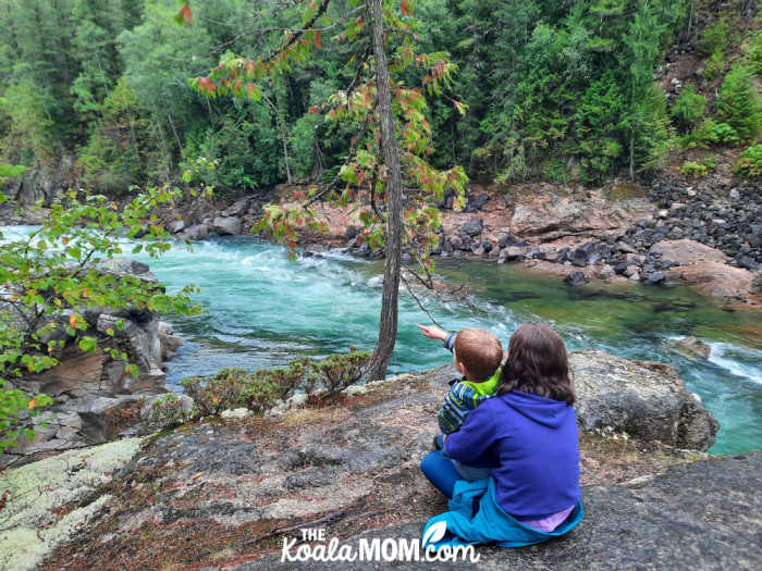 Teen holds her toddler brother in her lap while watching the Clearwater River.