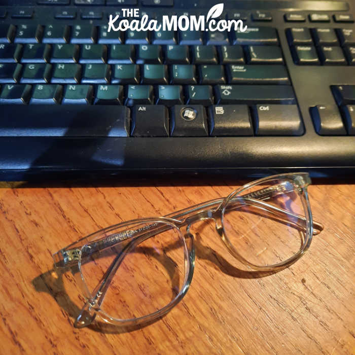 A pair of glasses sits in front of a computer keyboard.