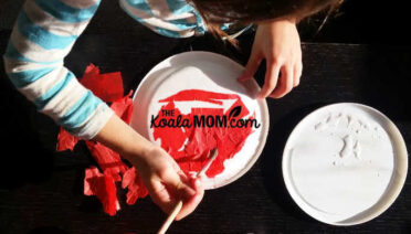 Child creating art with tissue paper and glue.