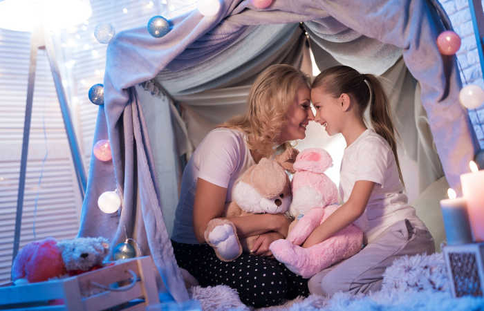 Making a blanket fort to play in, like this mom and daughter, is a great kids activity.