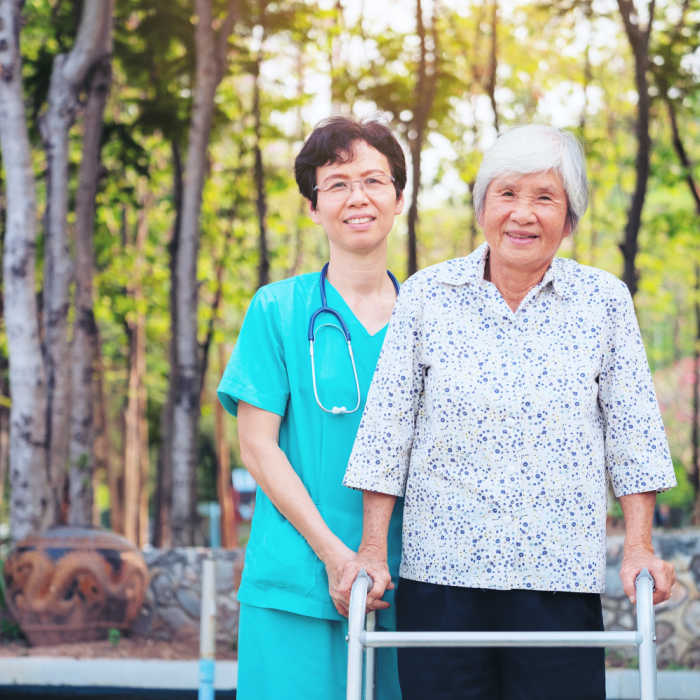 Nurse helps an elderly woman with her walker.