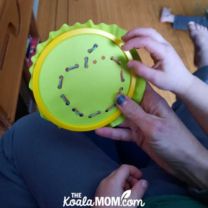 Preschooler sews an apple design with a fat needle and sturdy thread.