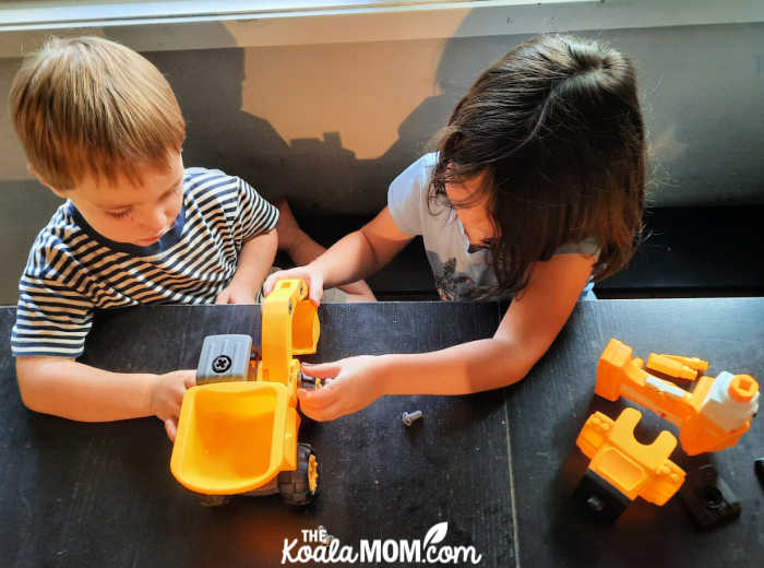 Boy and a girl playing with toy backhoe together.