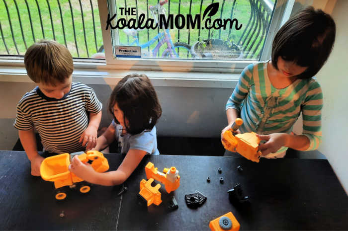 Three kids playing with construction toys together.