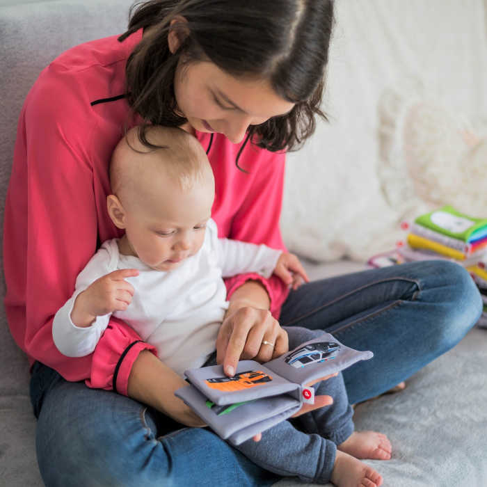 Mom reading a book to her baby. Photo via Pixabay.