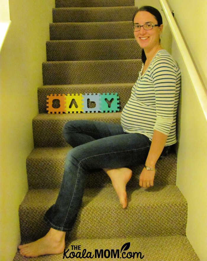 Smiling pregnant mom sitting on stairs wearing an EverlyGrey maternity shirt.