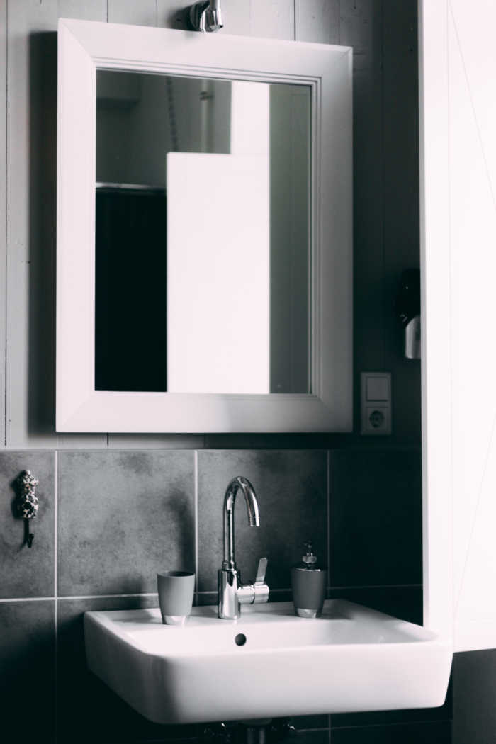 Simple bathroom vanity with mirror. Photo by Matthis on Pexels.