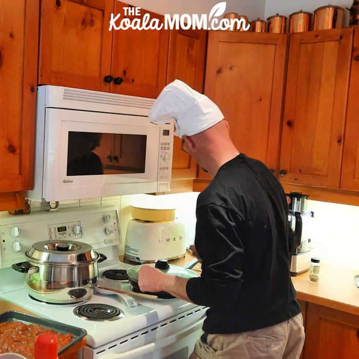 Man in a chef's hat cooking dinner at a stove.