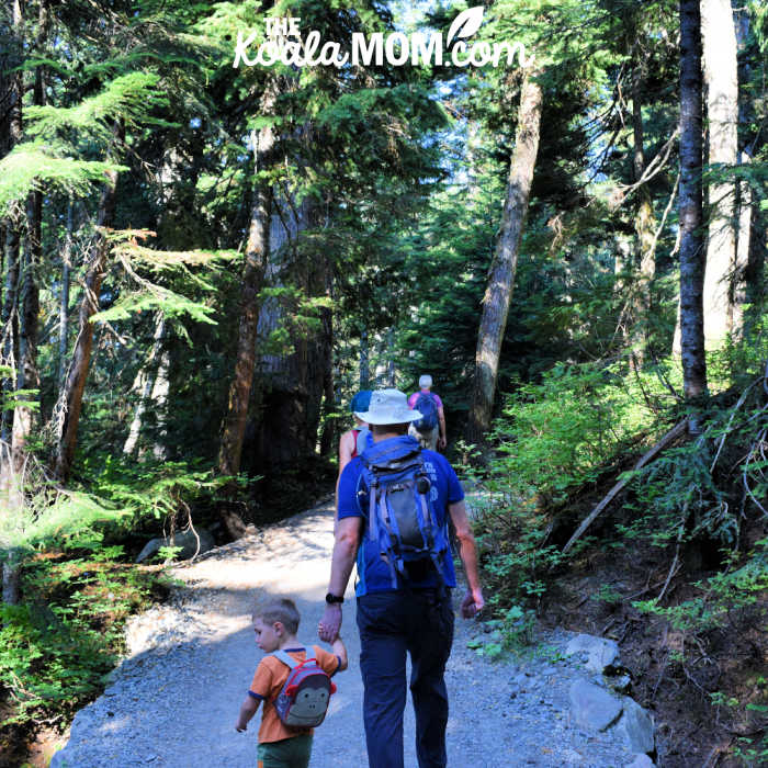 Boy holds a man's hand as he hikes.