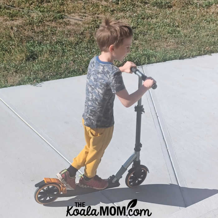 Boy having fun on his orange McLaren scooter.