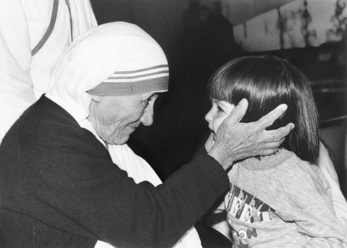 Photo of Mother Teresa smiling at a girl in front of her.