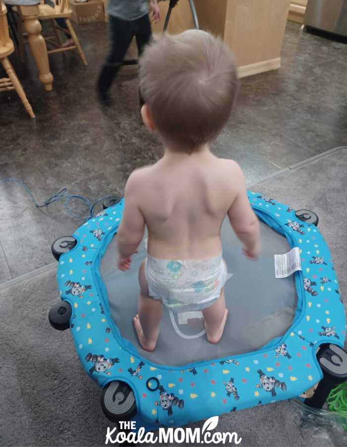 Toddler in a diaper standing on his TekyGo! bouncer.
