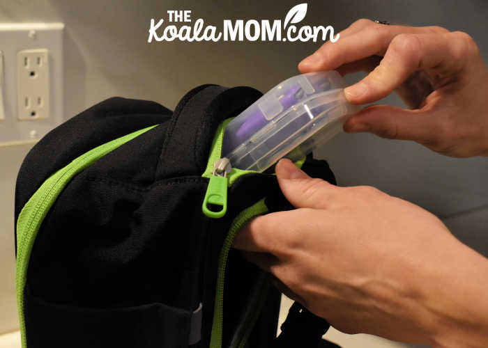 Mom putting a set of folding cutlery in a small pocket on her TiniBag.