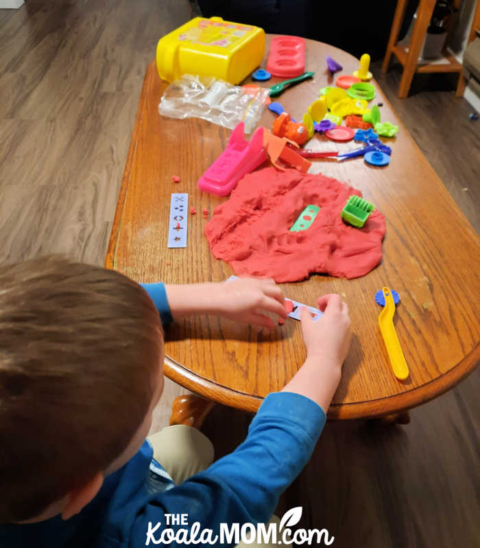 Boy playing with homemade red play dough.
