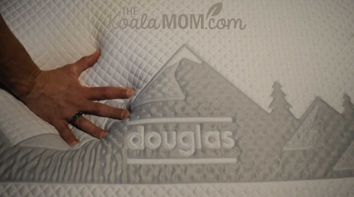 Hand pressing into soft firmness of an original Douglas mattress-in-a-box.