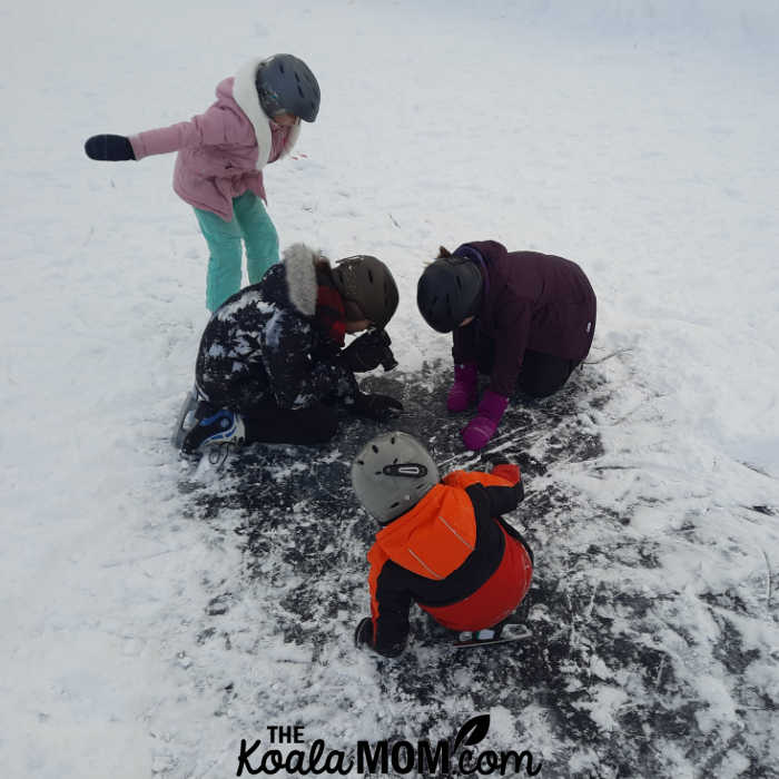 Kids studying the black ice under the snow at Lake Louise.