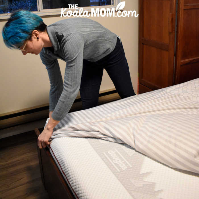 Mom pulling a fitted sheet over her Douglas queen mattress.