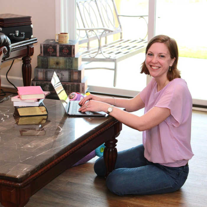 Taryn DeLong, WAHM and editor-in-chief, works on her laptop at her coffee table.