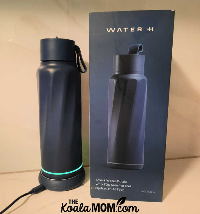 Blue WaterH bottle on its charging stand beside the box.