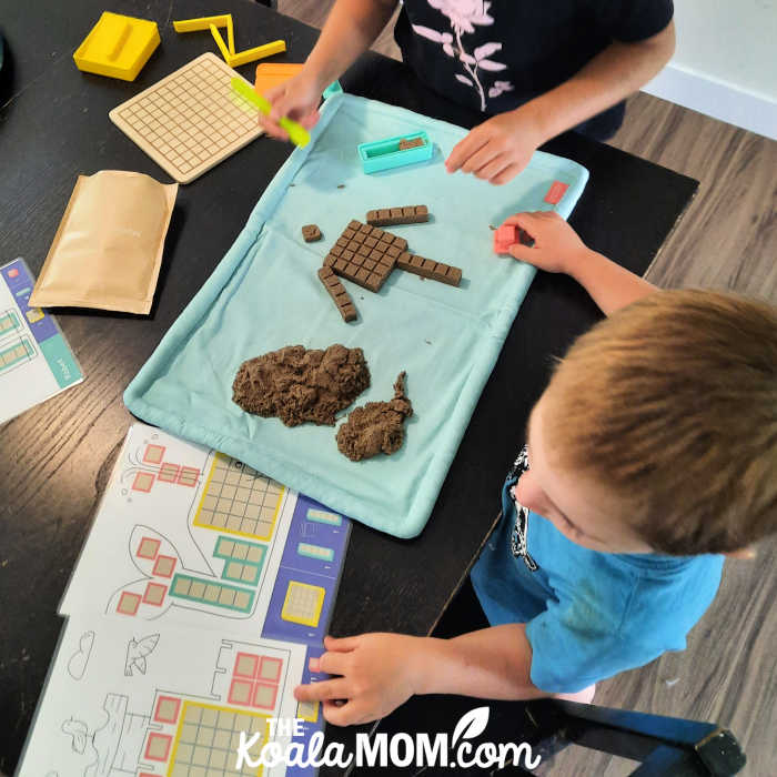 4-year-old playing with his kinetic sand to make a sand block robot.