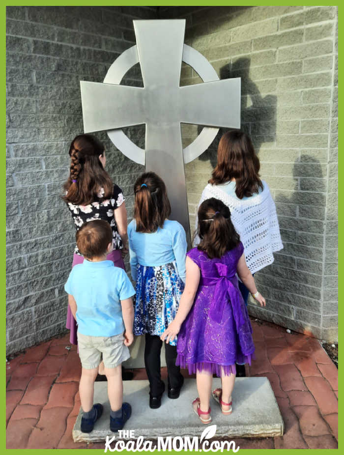 Five children dressed in their Easter best looking at a steel cross. Photo by Bonnie Way.