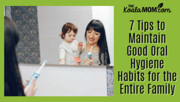 7 Tips to Maintain Good Oral Hygiene Habits for the Entire Family. Photo of mom holding her toddler on her hip while looking at her electric toothbrush by prostooleh via Freepik.