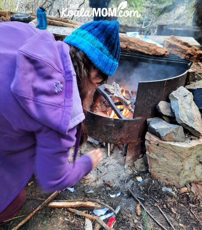 Teen makes a campfire.