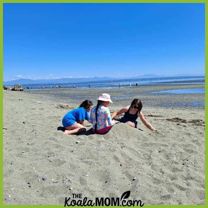 Three girls play in the sand at the beach. Photo by Bonnie Way.