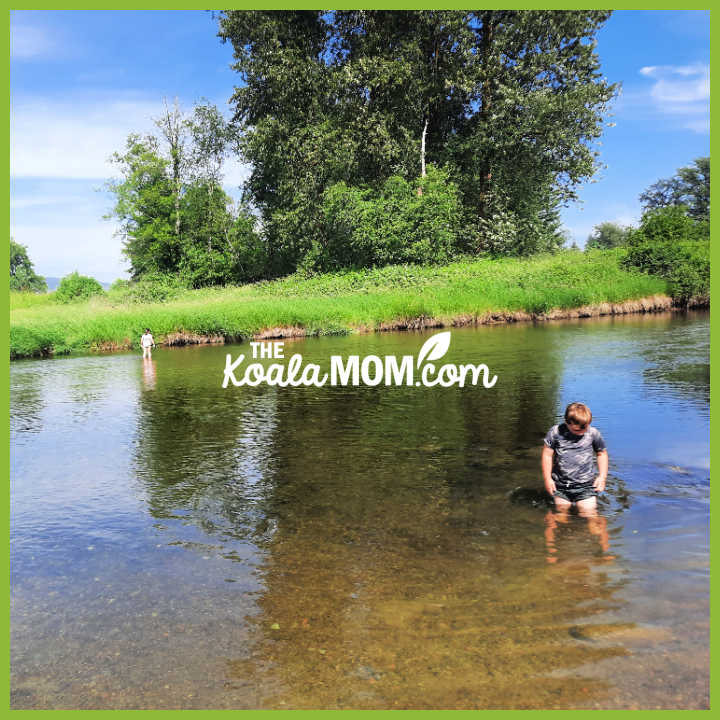 Two kids wade in a wide, shallow river. Photo by Bonnie Way.