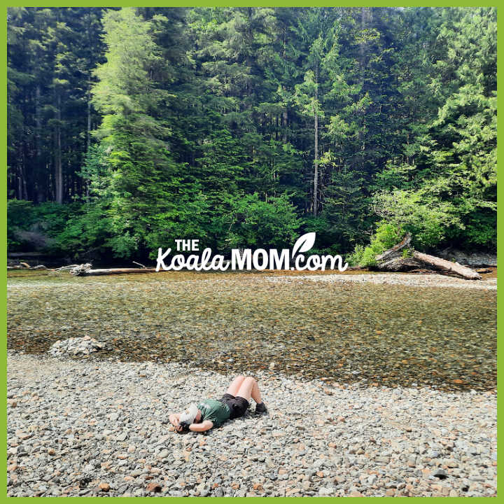 Teenager lays on the rocky beach of a small river. Photo by Bonnie Way.