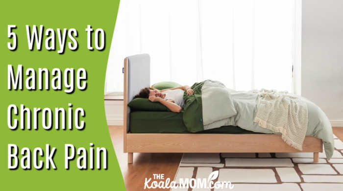 5 Ways to Manage Chronic Back Pain. Stock photo of woman sleeping on bed with green sheets in front of large curtained windows.