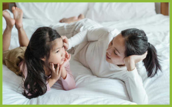 Photo of mom and daughter talking together on a white bedspread by Ketut Subiyanto via Pexels.