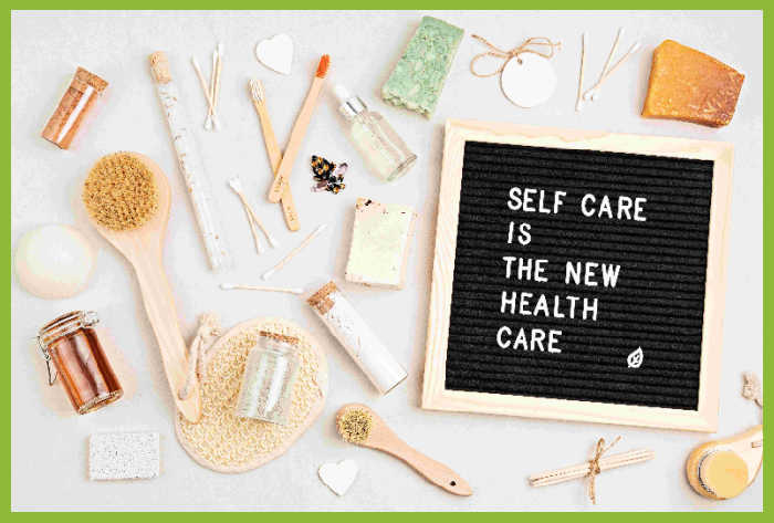 Stock photo of blackboard that says "self care is the new health care," surrounded by self-care items.