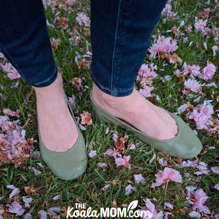 Woman in jeans stands on a flower-strewn lawn wearing a pair of olive green Tieks ballet flats. Photo by Bonnie Way.