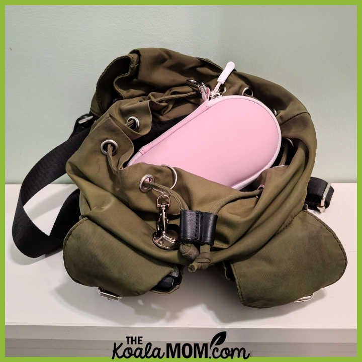Pink Lolalet glasses case peeking out of green backpack purse. Photo by Bonnie Way.